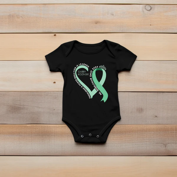 A baby onesie with Gabby's logo is in front of a wooden palette background.
