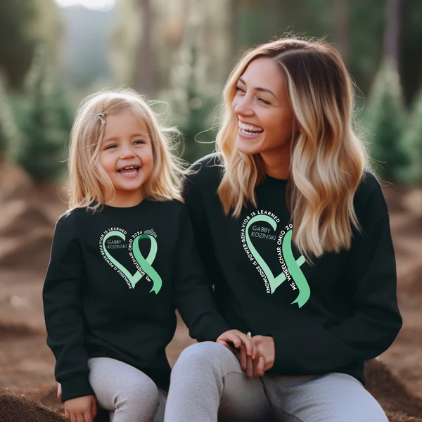 A mother and daughter are wearing sweatshirts with Gabby's logo on them.