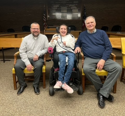 Gabby is wearing her sash while sitting next to two men, Bucyrus Mayor Bruce Truka and his assistant.
